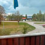 Blick von Balkon mit schwedischer Flagge auf Dorf und See.