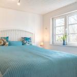 Schlafzimmer mit Bett, Fenster und Blumen