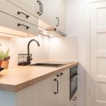 Küche mit Holz-Arbeitsplatte, Edelstahl-Spüle und integriertem Ofen.