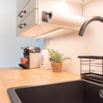 Küche mit Arbeitsplatte, Spüle, Wasserhahn und Küchenutensilien.