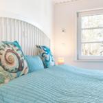 Schlafzimmer mit Bett, Kissen und Fenster. Auf dem Fensterbrett steht eine Vase.