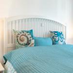 Schlafzimmer mit Bett, Kissen und Nachttisch mit Lampe.