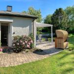 Haus mit Terrasse, Garten und Blick auf Wald. Eingangsbereich mit Blumen.