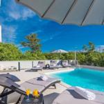 Pool area with loungers and umbrellas under blue sky.