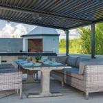 Terrace with seating group, dining table, and grill area under roof.