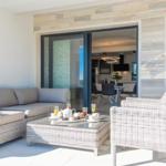 Terrace with sofa, table and chairs. Entrance to the interior of the house.