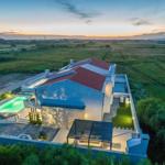 Modern villa with pool and terrace in rural setting at sunset.