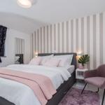 Bedroom with bed, chair, and window with curtains.