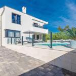 Modern villa with pool and terrace. Garage and plants are visible.