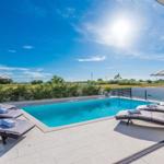 Pool area with loungers and umbrellas under blue sky.