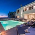 Modern villa with pool and loungers at night.