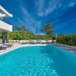 Pool with lounge chairs and umbrellas next to modern house.