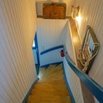 Holztreppe mit blauer Balustrade, Wandbeleuchtung und alter Kiste.