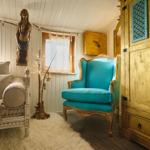 Ein Raum mit einem blauen Sessel, einem Sofa und einem großen Schrank.