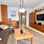 Wohnzimmer mit Sofa, Couchtisch und Fernseher an der Wand.