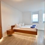 Schlafzimmer mit Doppelbett, Holzmöbel und Fenster.