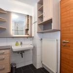 Badezimmer mit Waschbecken, Spiegel und Holzschränken.