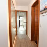 Flur mit Holzboden, Tür zu Bad und Schlafzimmer, Wandbild und Intercom.