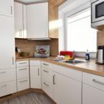 Küche mit weißen Schränken, Holzoberflächen und integriertem Mikrowellenherd.