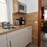 Küche mit Spüle, Mikrowelle und Kaffeemaschine. Durchgang zu Essbereich mit Tisch und Stühlen.