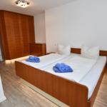 Schlafzimmer mit Doppelbett, Holzmöbel und Holzdielenboden.