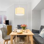 Esszimmer mit Tisch, Stühlen und Sofa. Blumenvase und TV sind sichtbar.