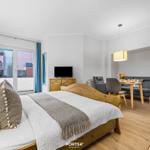 Schlafzimmer mit Bett, TV und Blick auf Balkon. Wohnbereich mit Sofa und Esstisch.