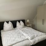 Schlafzimmer mit Doppelbett, weißen Nachttischen und Kleiderschrank.