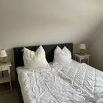 Schlafzimmer mit Doppelbett, zwei Nachttischen und Decke. Dachschräge im Hintergrund.