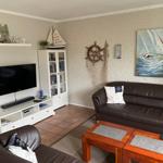 Wohnzimmer mit Sofa, Fernseher und Seemotiven an der Wand.