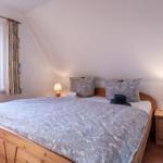 Schlafzimmer mit Holzbett, zwei Nachttischen und Fenster mit Blick.