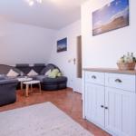 Wohnzimmer mit Sofa, Sessel und Sideboard. Wandbild und Teppich sind sichtbar.