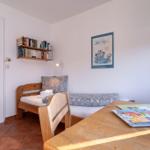 Ein Schlafzimmer mit Holzbett, Tisch und Bücherregal an der Wand.