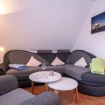 Ein Wohnbereich mit einem grauen Sofa, zwei runden Tischen und einer Stehlampe.