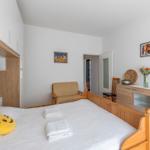 Schlafzimmer mit Holzbett, Kleiderschrank und Stuhl. Auf Bett liegen Handtücher und Kissen.