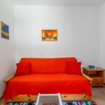 Ein Raum mit einem roten Sofa, zwei Kissen, einem Holztisch und zwei Wandbildern.