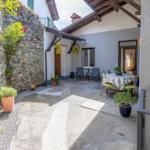 Terrasse mit Tisch, Stühlen und Pflanzen an Steinmauer und Hauswand.