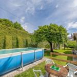 Blauer Pool im Garten mit Tisch, Stühlen und grüner Hecke.