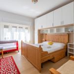 Schlafzimmer mit Holzbett, Babybett und weißen Schränken.