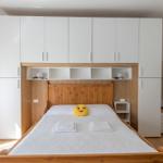Schlafzimmer mit Bett, weißen Schränken und Holzgestell.
