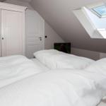 Schlafzimmer mit Dachfenster, Bett und Schrank. Wandbild und Nachttisch sind sichtbar.