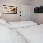 Schlafzimmer mit Bett, Wandbild, TV und Lampen.