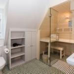 Badezimmer mit Sauna, Toilette und Waschbecken. Holzsauna mit Glaswand.