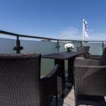 Terrasse mit Tisch und Stühlen, Blick auf Flagge und Himmel.
