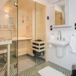 Sauna mit Glaswand, Waschbecken und Fliesenboden.