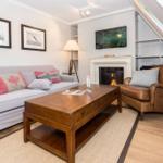 Wohnzimmer mit Sofa, Ledersessel, Kamin und Fernseher unter Dachschräge.