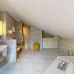 Badezimmer mit Badewanne, Waschbecken und Dusche unter Dachschrägen.