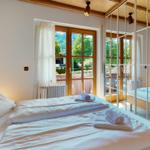 Schlafzimmer mit Bett, Spiegelschrank und Fenster zum Garten.