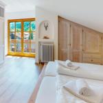 Zimmer mit zwei Betten, Holzmöbeln und Blick auf die Berge.