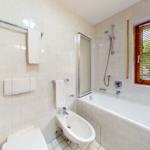 Badezimmer mit Badewanne, Dusche, Toilette und Bidet. Fenster mit Jalousie.